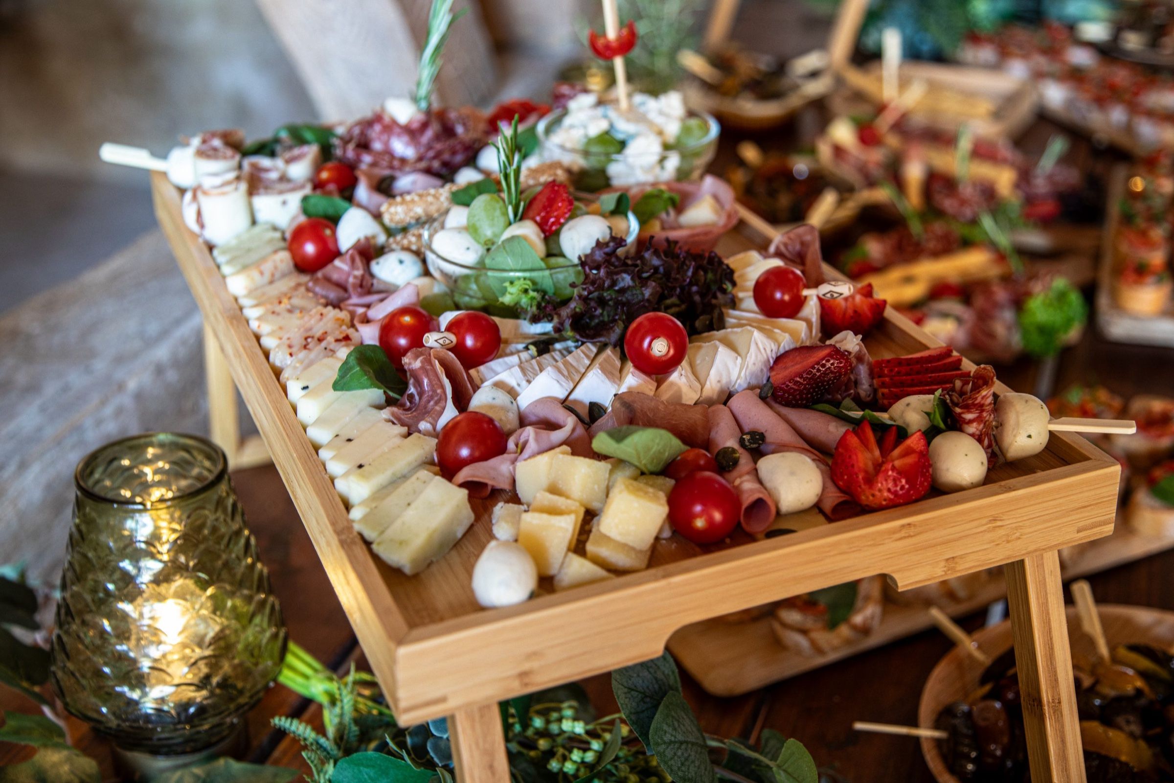 Holztablett mit Schinken, Käse, Mozzarellakugeln, Kirschtomaten und Erdbeeren