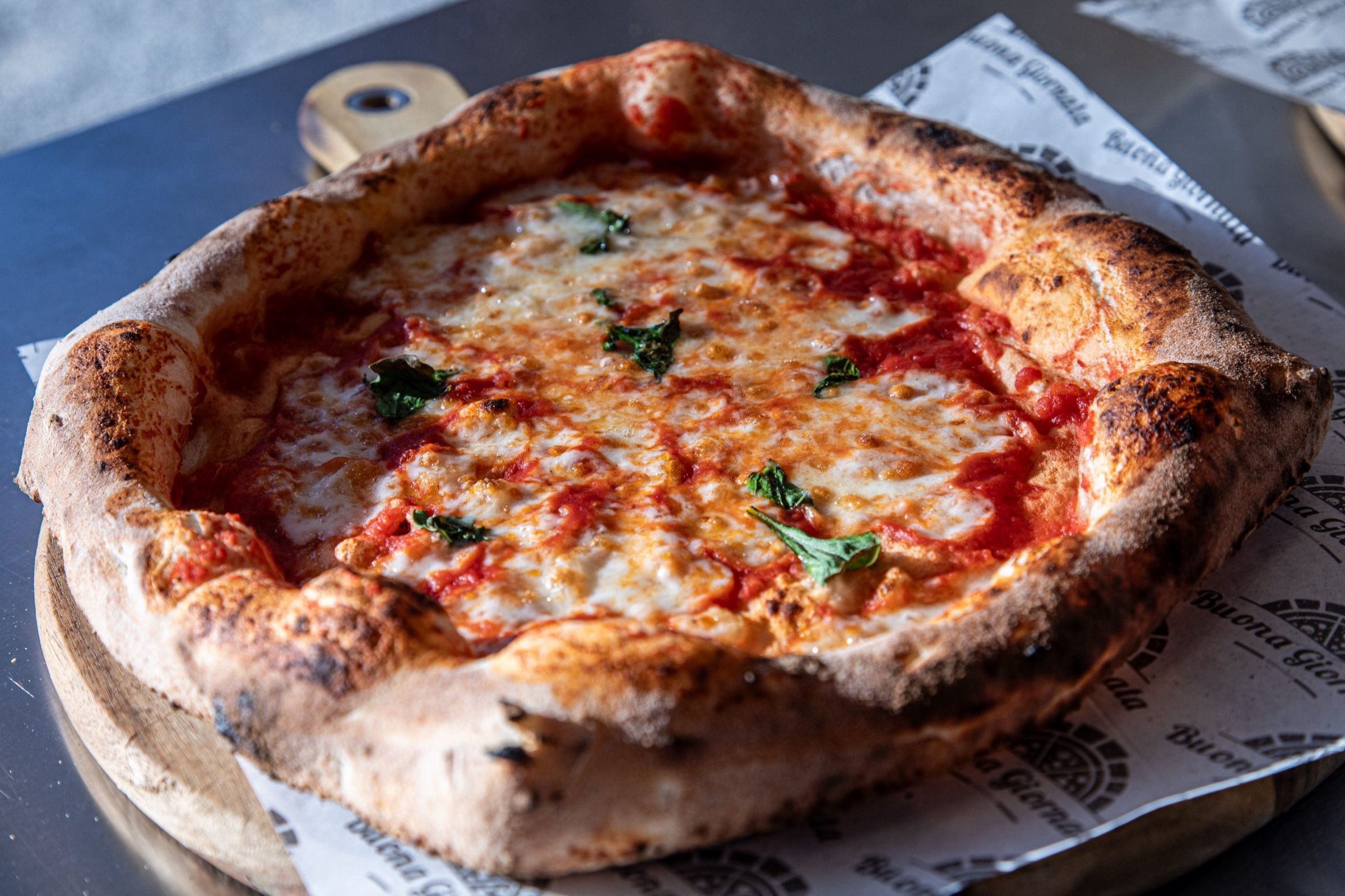 Neapolitanische Pizza mit Tomatensauce, geschmolzenem Mozzarella und Basilikum auf einem Holzbrett