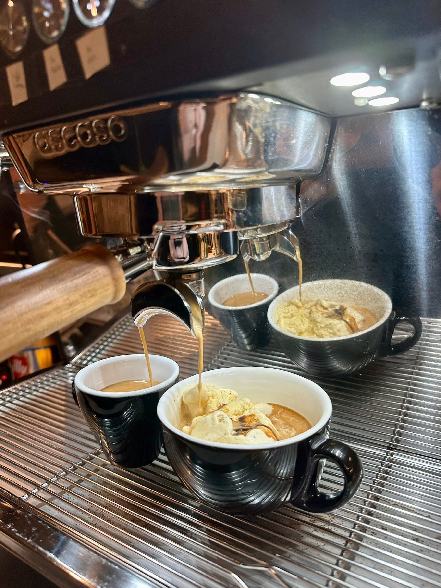 Espresso läuft aus einer Siebträgermaschine in vier Tassen, zwei davon mit Eis